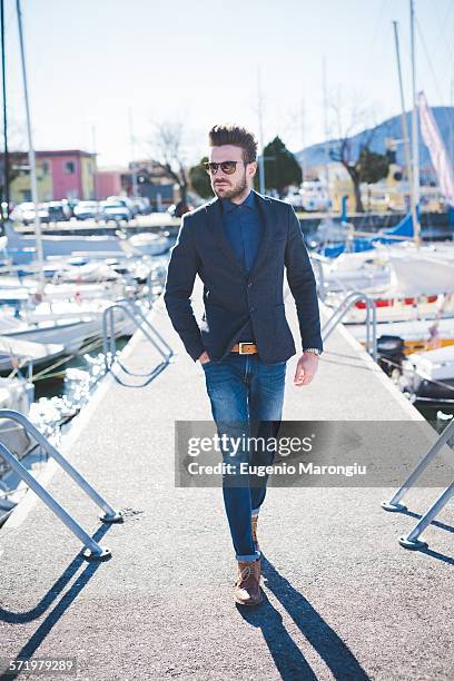 young man with hand in pocket walking on lake pier - veste de costume photos et images de collection
