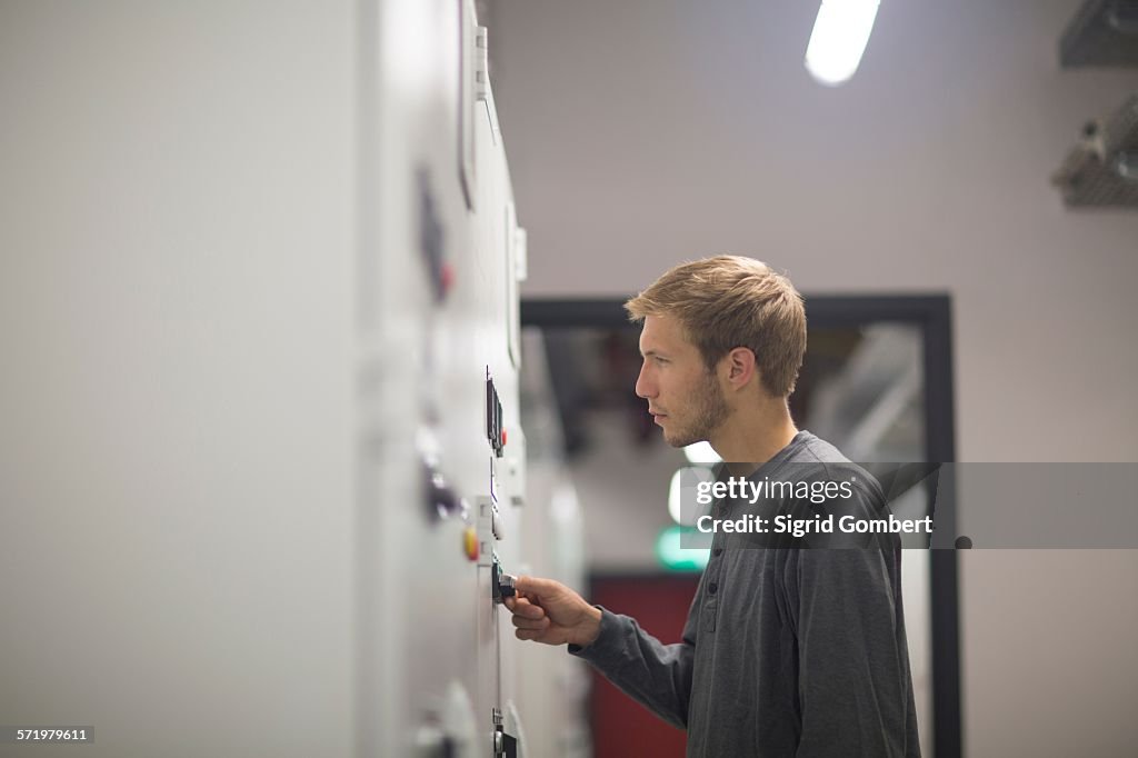 Young male technician turning switch in technical room