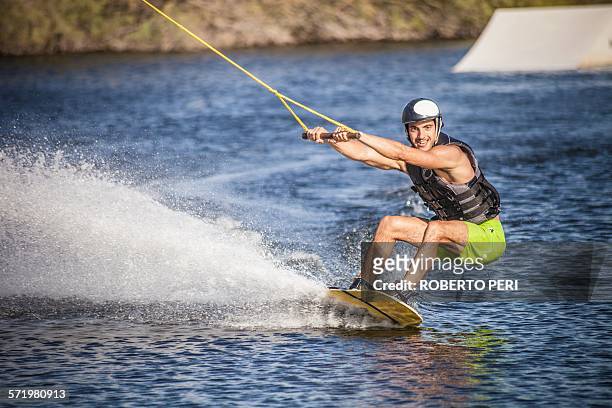 mid adult man swerving on wakeboard in sea, cagliari, sardinia, italy - wasserskifahren stock-fotos und bilder
