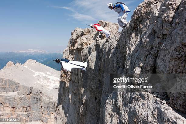 three male base jumpers exiting from mountain top, dolomites, italy - base jumping imagens e fotografias de stock