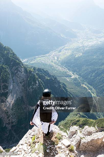 male base jumper in wingsuit standing on edge of mountain, dolomites, italy - base jumping imagens e fotografias de stock