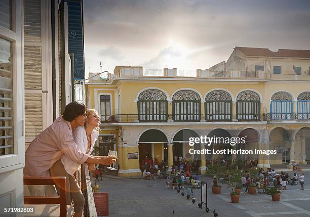 romantic young couple looking out from restaurant balcony in plaza vieja, havana, cuba - cuba fotografías e imágenes de stock