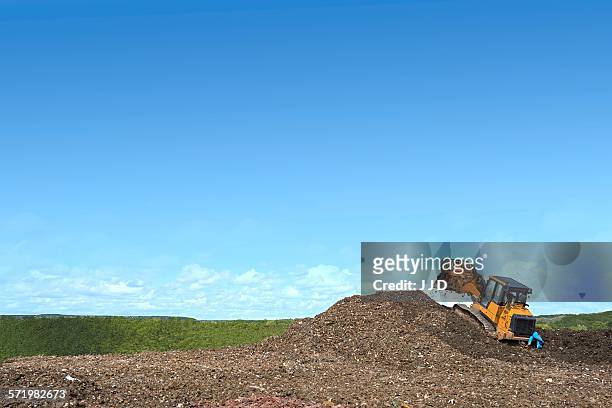 digger on mound burying waste on landfill site - landfill foto e immagini stock