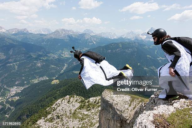 two male base jumpers exiting from mountain top, dolomites, italy - außergewöhnliche sportarten stock-fotos und bilder