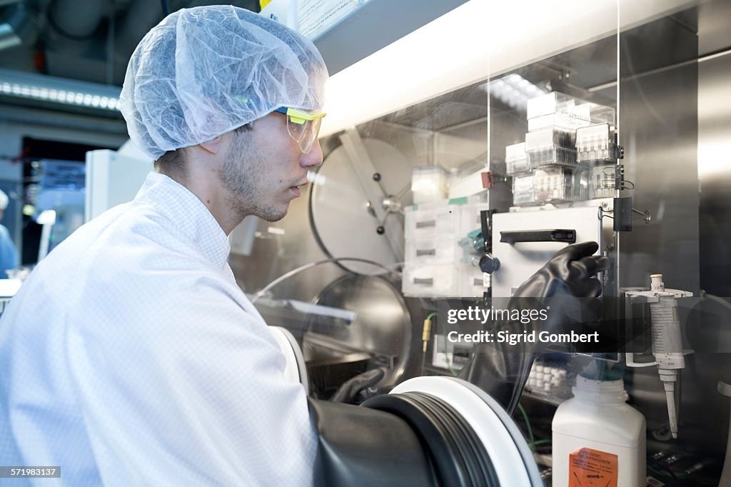 Male scientist adjusting switch in fume hood in lab cleanroom
