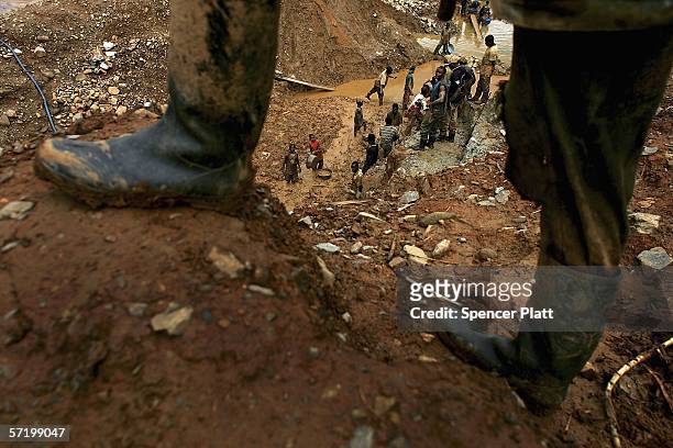 Line of men pass up buckets of dirt and mud while looking for gold at an abandoned industrial mine on March 28, 2006 in Mongbwalu, CongoThousands of...