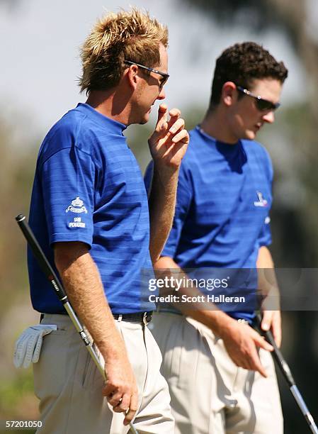 Teammates Ian Poulter and Justin Rose of England wait on the ninth green during the second day of the Tavistock Cup at the Isleworth Golf and Country...