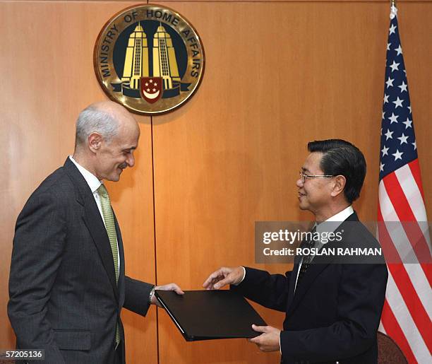 Home Security Secretary Michael Chertoff exchanges document with Singapore Minister for Home Affairs Wong Kan Seng after a signing of intent between...