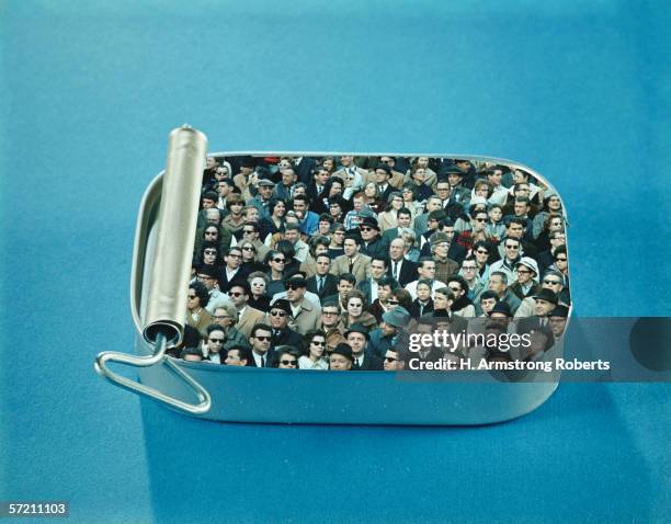 1960s: Crowd of men and women packed inside open sardine tin.