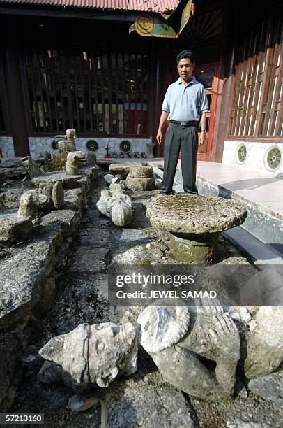 An employee of a museum shows a stone statute which was damaged during last year earthquake in Gunung Sitoli, on Nias island, 08 March 2006. The...