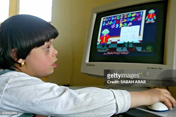An Iraqi child with Down Syndrome plays on the computer at al-Rajaa Institute for Special Needs, 27 March 2006. The institute was founded back in...