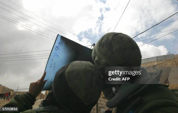 Israeli soldiers watch the partial eclipse of the sun using an old X-ray in the divided West Bank town of Hebron, 29 March 2006. The eclipse, caused...