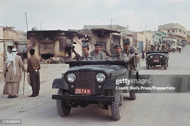 Soldiers and troops of the Israel Defense Forces in a small convoy of Willys jeeps drive past as citizens of the Jordanian West Bank town of Qalqilya...