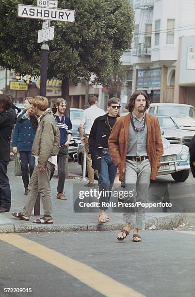 View of hippies and young people standing and walking across a sidewalk at the intersection of Haight and Ashbury streets in the Haight-Ashbury...