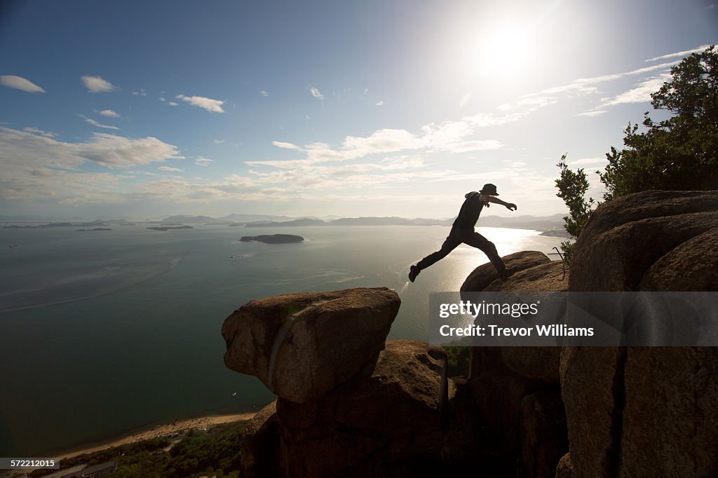 A man jumping between 2 rocks on a mountain top