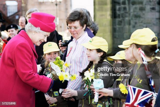 Queen Elizabeth II is given daffodils by local Brownies during a walkabout in the Market Square on March 31, 2006 in Staffordshire, England.