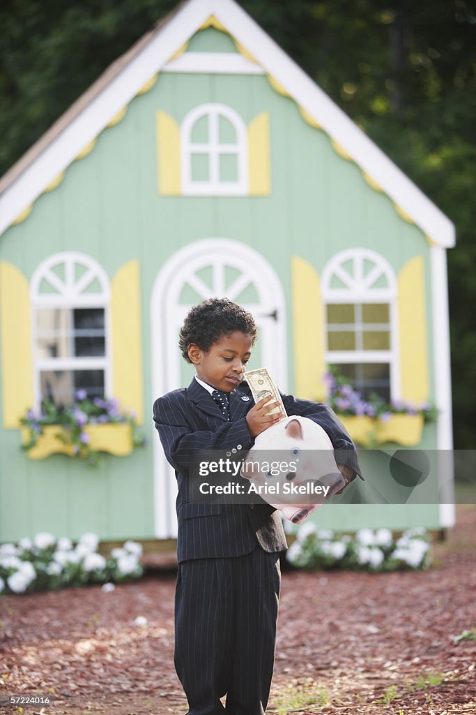 Boy putting dollar in piggy bank