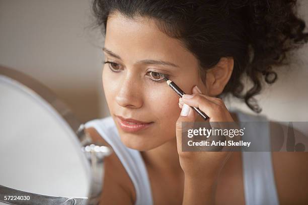 woman putting on make-up - eye liner stock-fotos und bilder