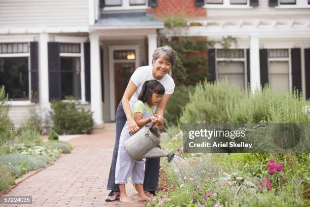 woman and child watering garden - asian grandmother stock pictures, royalty-free photos & images