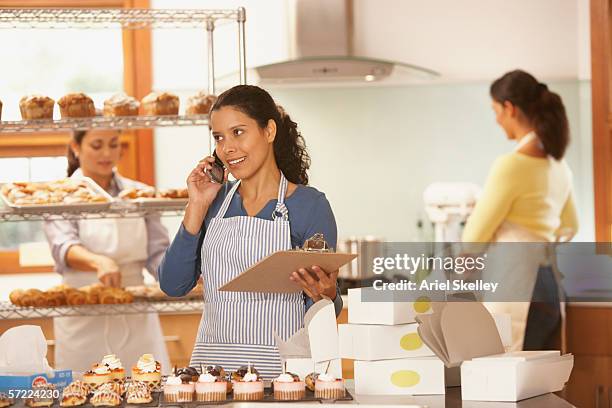 woman talking on phone while working in bakery - young women group back stock-fotos und bilder