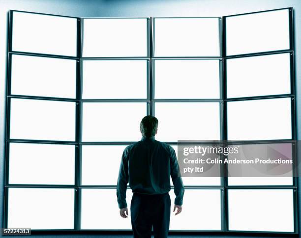 man looking at a wall of flat screen monitors - screen partition stock pictures, royalty-free photos & images