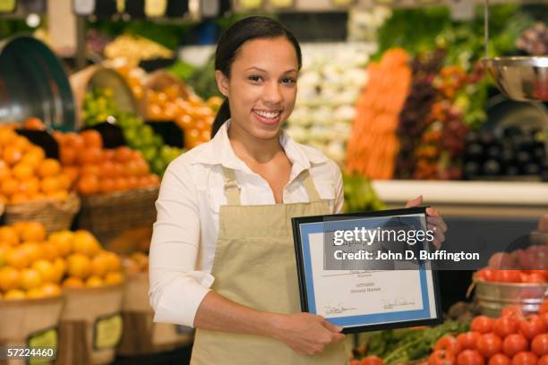 portrait of grocery employee holding employee of the month plaque - werknemer-van-de-maand stockfoto's en -beelden