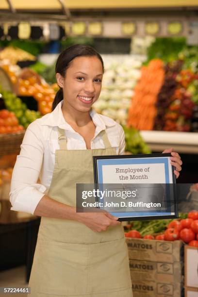 portrait of grocery employee holding employee of the month plaque - employee of the month plaque stock pictures, royalty-free photos & images