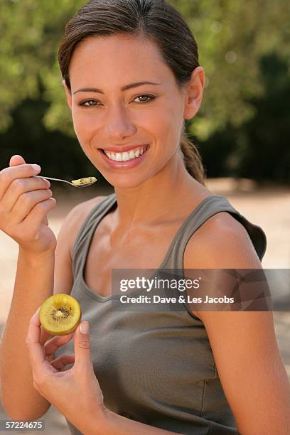 young woman eating kiwi - kiwi foto e immagini stock