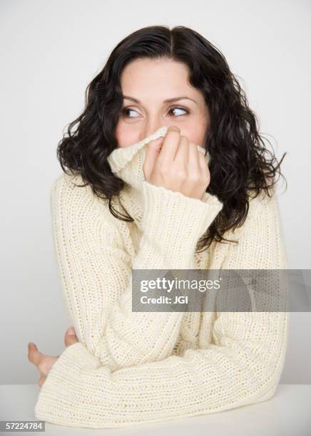 portrait of woman covering mouth with sweater - gesicht verstecken stock-fotos und bilder