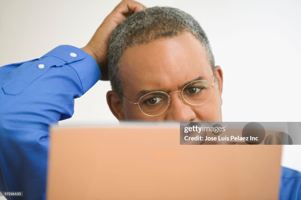 Close up of mature man with laptop scratching head