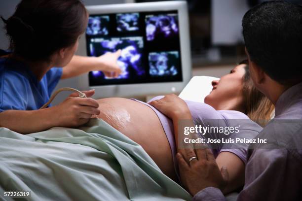 female doctor pointing to ultrasound picture with pregnant woman - ultraljud bildbanksfoton och bilder