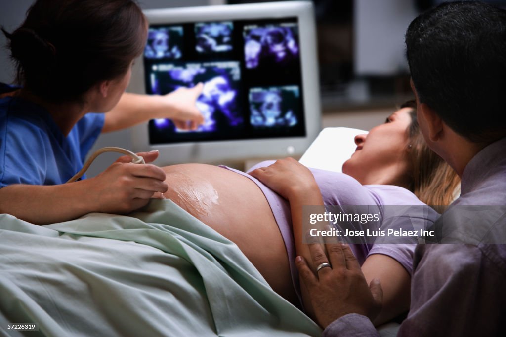 Female doctor pointing to ultrasound picture with pregnant woman