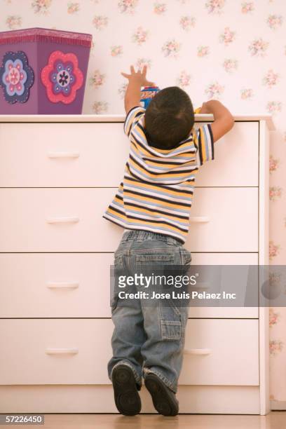 young boy reaching on dresser - schleichen stock-fotos und bilder