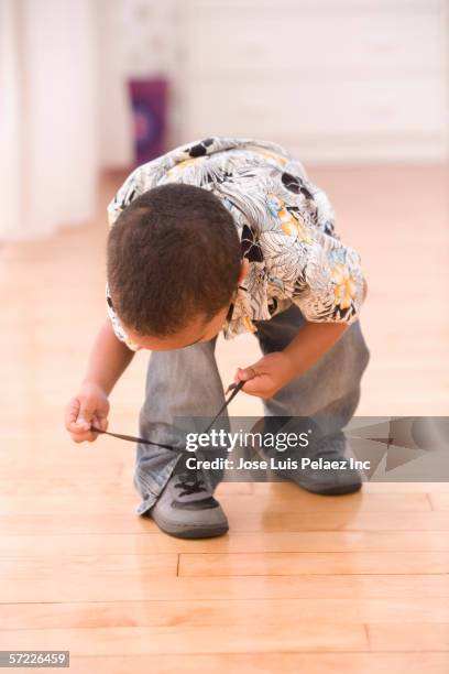 young boy bent over tying shoe - boy tying shoes stock-fotos und bilder