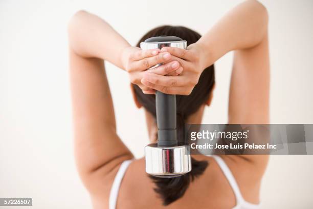 rear view of woman exercising with dumbbell behind head - dumbells isolated stock pictures, royalty-free photos & images