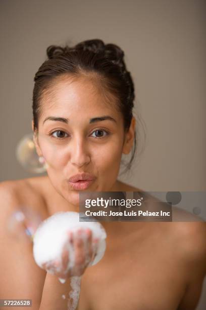 close up portrait of woman blowing soap bubble - frau gesicht schaum stock-fotos und bilder