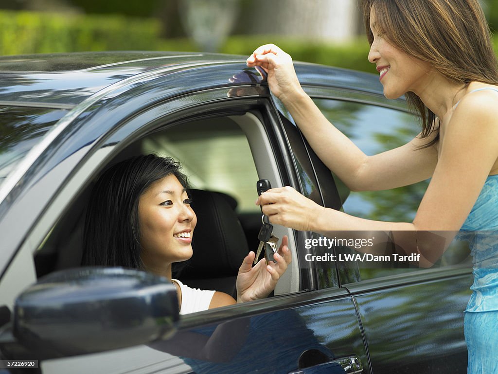 Mother handing teenage daughter car keys