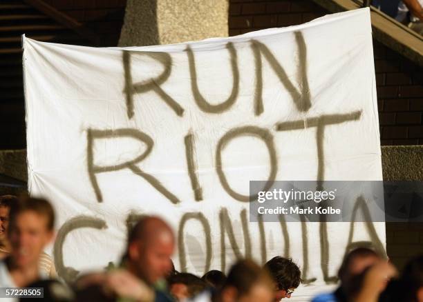 Supporters in the crowd hold up a banner in reference to the riots on Crunulla Beach during the round four NRL match between the Cronulla-Sutherland...