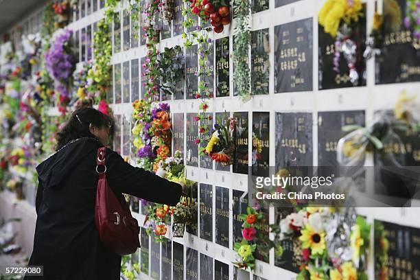 Chinese woman hangs flowers onto a tombstone at Babaoshan Cemetery to mark the Qingming Festival on April 1, 2006 in Beijing, China. The Qingming...