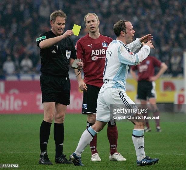 Referee Helmut Fleischer shows Fabian Ernst of Schalke the yellow card during the Bundesliga match FC Schalke 04 and Hamburger SV at the Veltins...