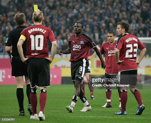 Referee Helmut Fleischer shows Timoothee Atouba of Hamburg the yellow card during the Bundesliga match FC Schalke 04 and Hamburger SV at the Veltins...
