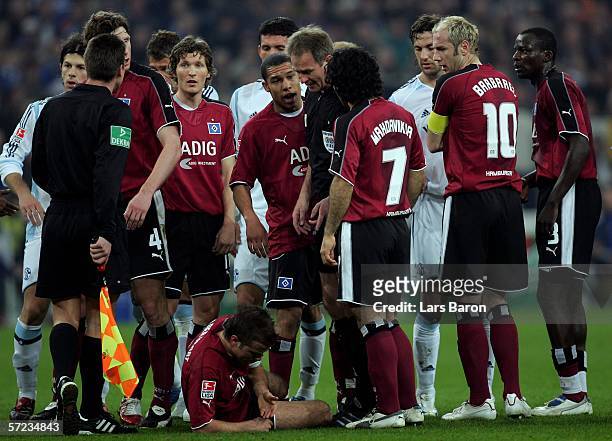 The Schalke and Hamburg players duscus with Referee Helmut Fleischer, while Rafael van der Vaart lies injured on the pitch, during the Bundesliga...