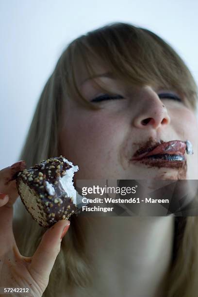 young woman eating chocolate marshmallow - licking lips stock pictures, royalty-free photos & images