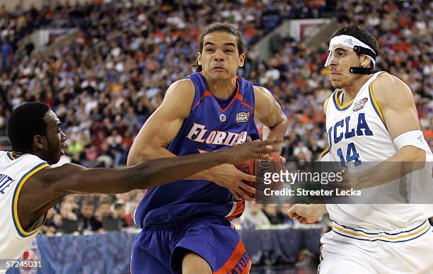 Joakim Noah of the Florida Gators drives on Luc Richard Mbah a Moute and Lorenzo Mata of the UCLA Bruins during the National Championship game of the...
