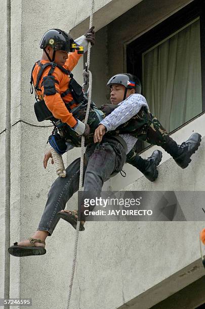 Government rescue worker abseils the wall of an hotel carrying a man acting as a victim during an annual fire and earthquake evacuation exercise in...