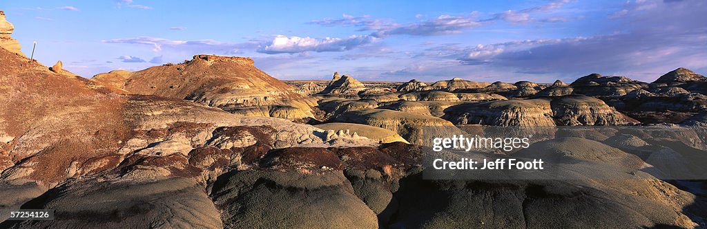 Three mounds rise under sky of clouds. Bisti Wilderness Area, Bureau of Land Management, New Mexico