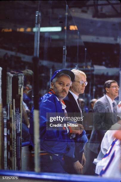 New York Islanders equipment manager Jim Pickard stands next to hockey sticks behind the bench during a game at Nassau Coliseum, Uniondale, Long...