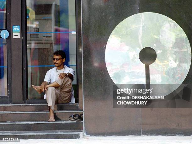 An Indian man sits beside an ATM counter of the State Bank of India, in Kolkata, 05 April 2006, as thousands of employees of the bank continued on...