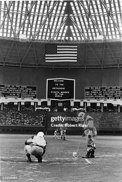 Groundskeepers are forced to wear 'futuristic' spacesuit uniforms as they prepare the diamond for the first game in the Astrodome, Houston, Texas,...
