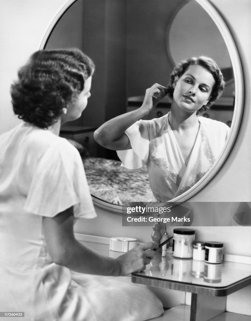Woman doing hair in front of mirror, (B&W)